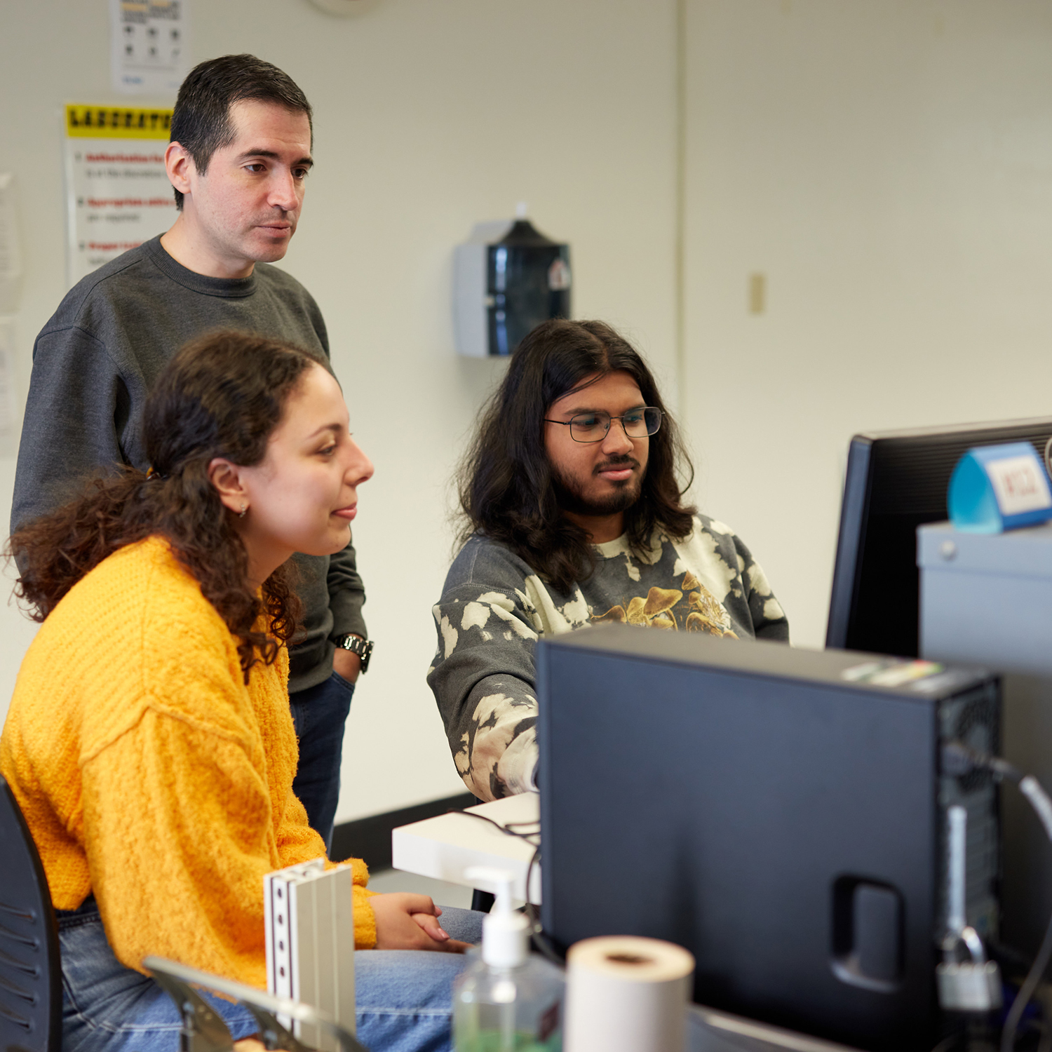 three people watching a computer screen
